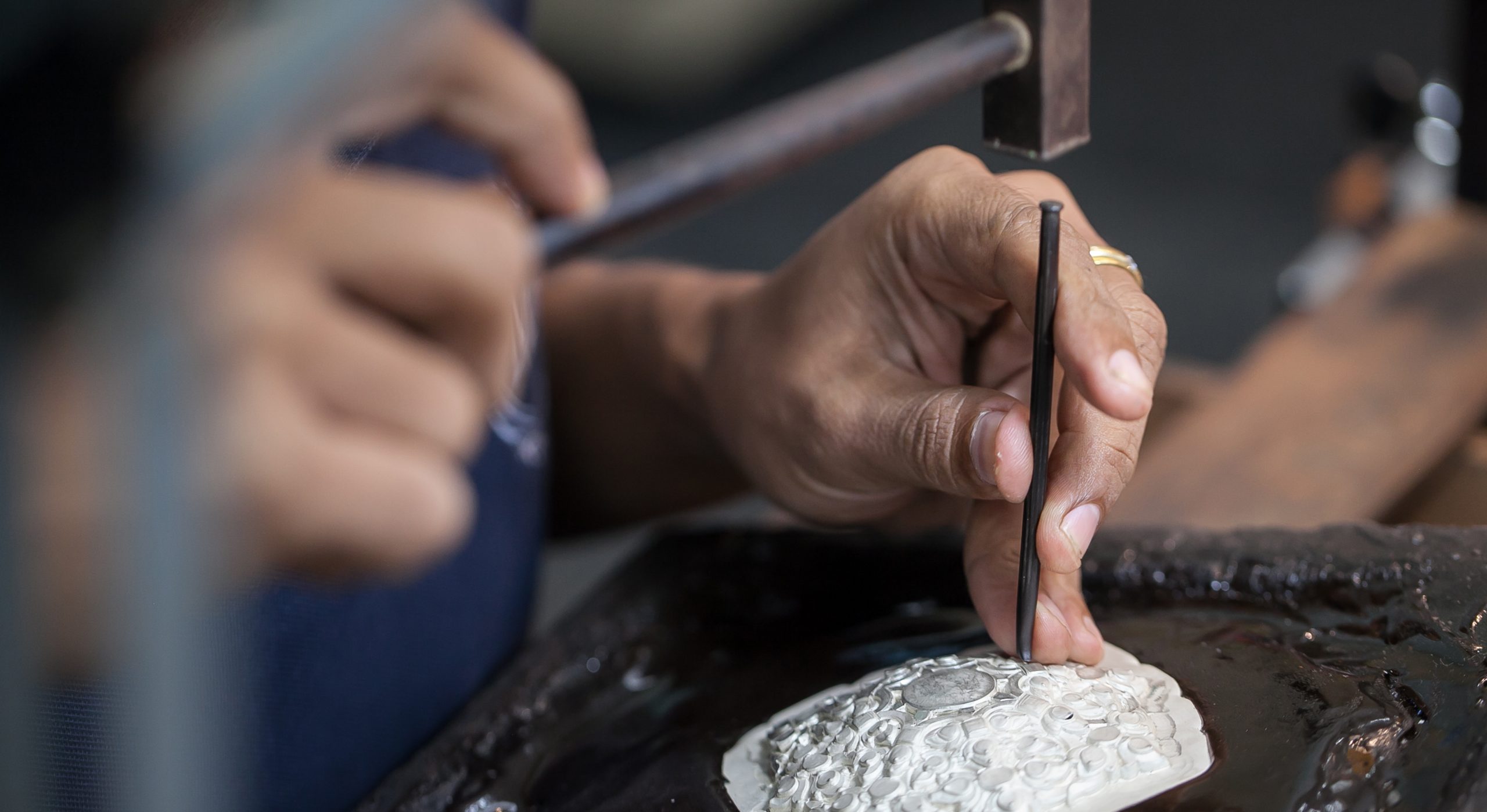 Silversmith using hammers and steel engraved pattern on silver